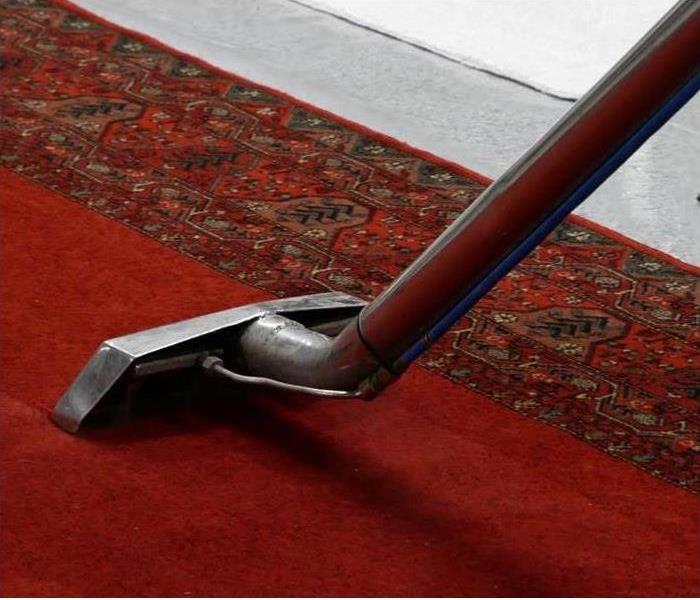 A vacuum cleaner is drying a carpet