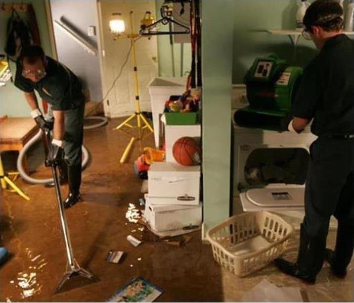 basement damaged by water, workers with vacuum extractor