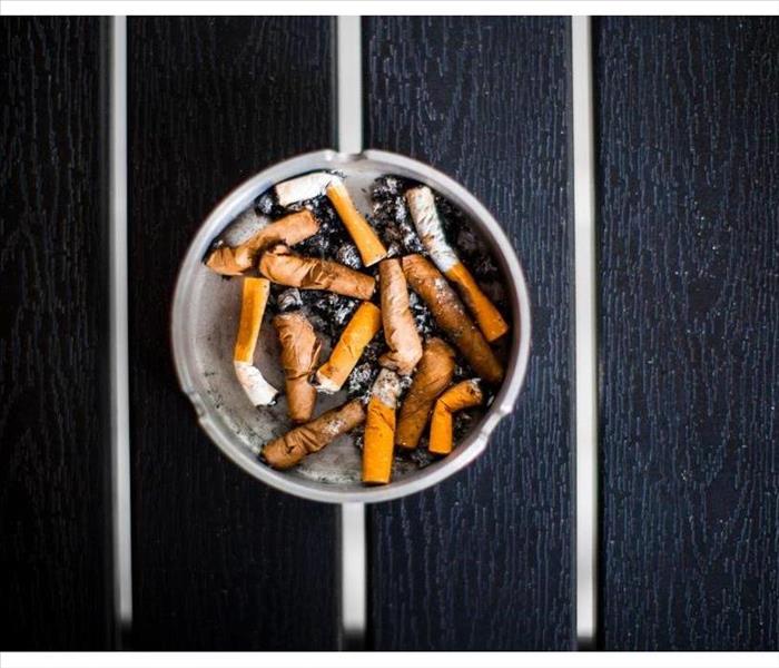 An ashtray with old smoked cigarettes stands on a black table top view, day